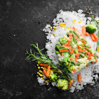 Assortment of frozen vegetables on ice. Stocks of food. Top view. Free space for your text.