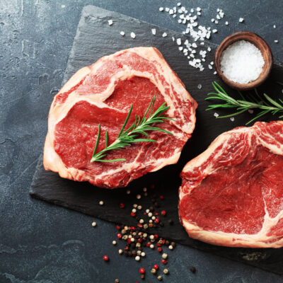 Fresh meat on slate black board top view. Raw beef steak and spi